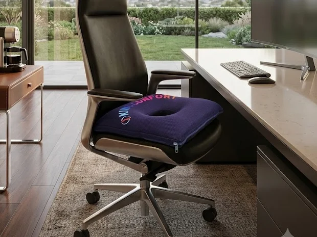 Coussin KinéConfort posé sur un fauteuil de bureau face à un plan de travail