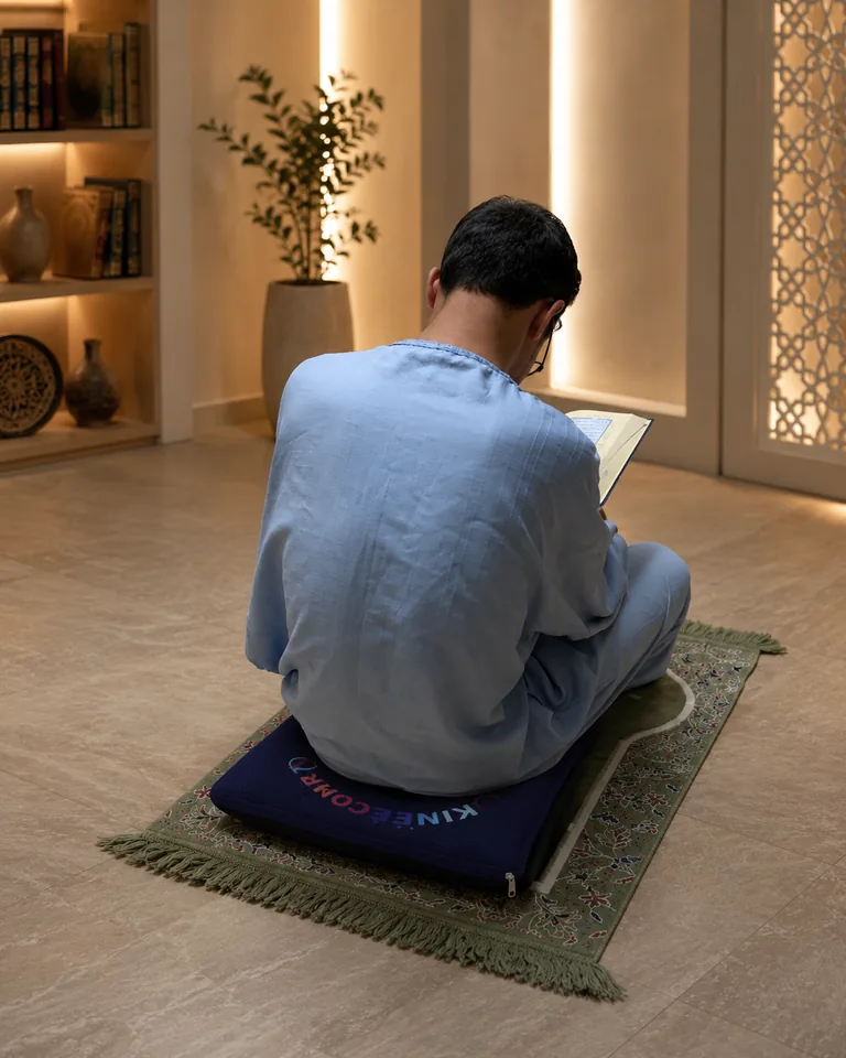 Personne assise sur le coussin KinéConfort pendant un moment de recueillement avec le Coran ouvert